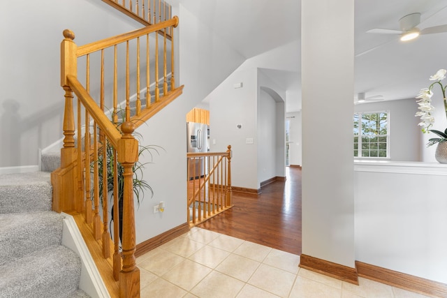 staircase with arched walkways, ceiling fan, baseboards, and tile patterned floors