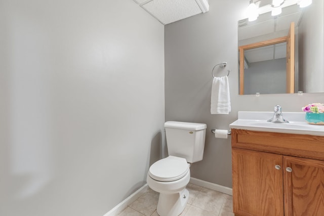 half bathroom featuring tile patterned flooring, baseboards, vanity, and toilet