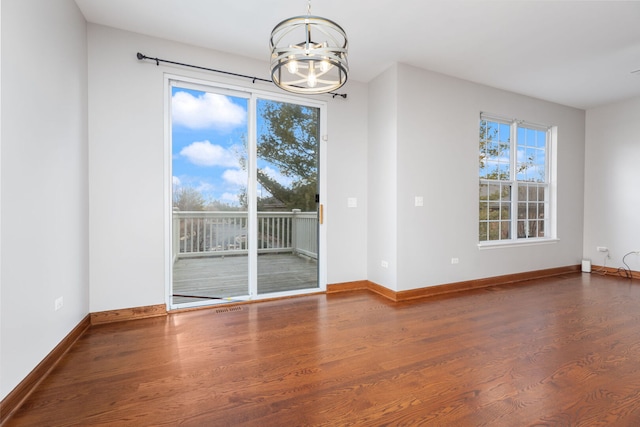 unfurnished dining area with an inviting chandelier, baseboards, and wood finished floors