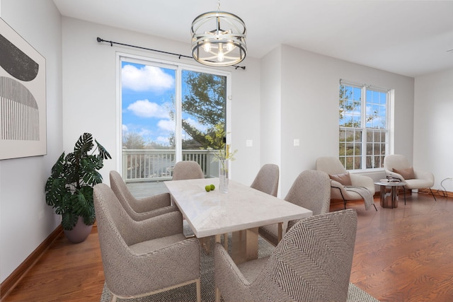 dining space featuring baseboards, a chandelier, and wood finished floors