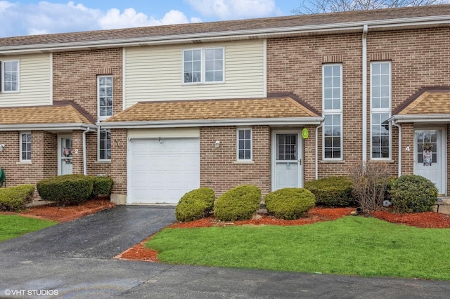 townhome / multi-family property featuring aphalt driveway, brick siding, a shingled roof, and an attached garage