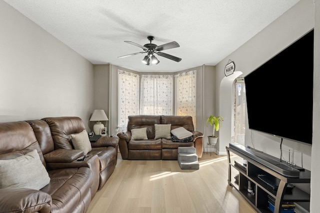 living area with a wealth of natural light, a textured ceiling, a ceiling fan, and wood finished floors