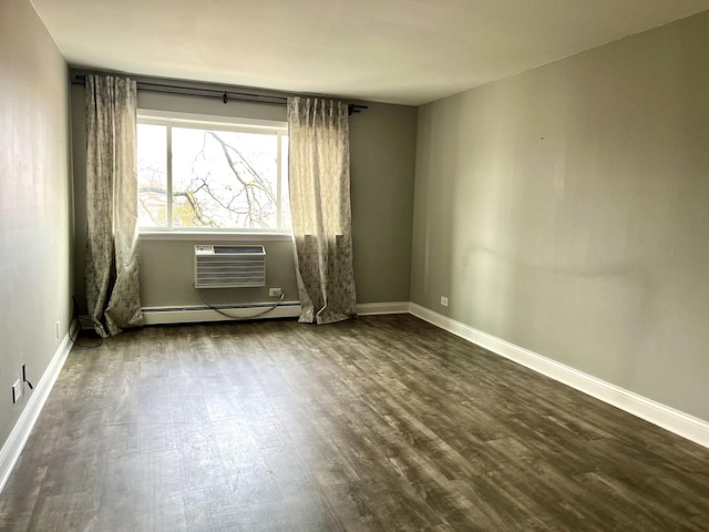 empty room featuring an AC wall unit, baseboards, dark wood-style flooring, and a baseboard radiator