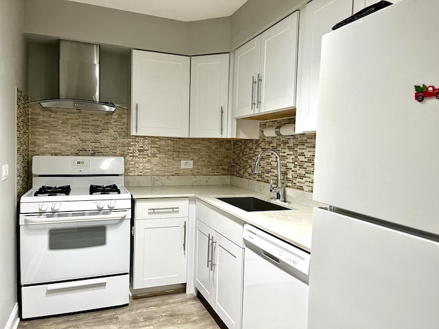 kitchen with a sink, white appliances, wall chimney exhaust hood, white cabinets, and light countertops