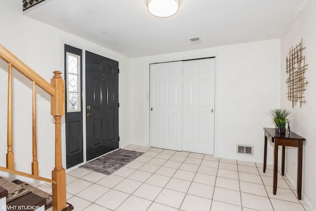 foyer entrance with stairway, light tile patterned flooring, and visible vents