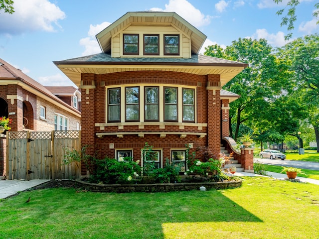 exterior space with a gate, brick siding, fence, and a front lawn