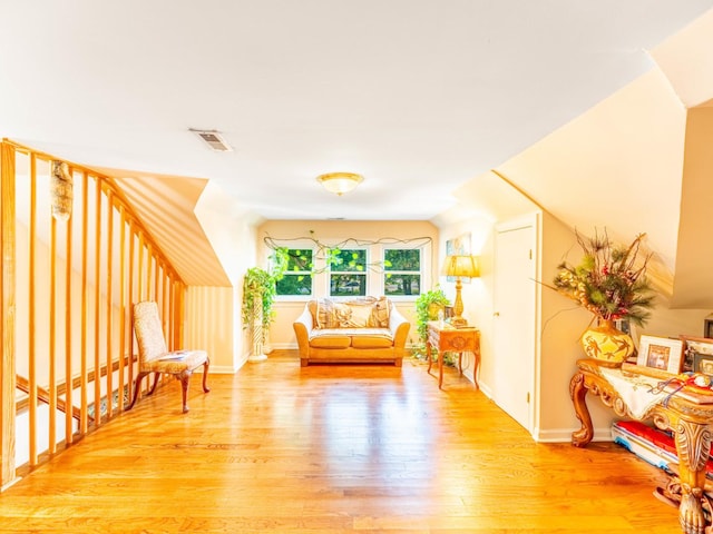 sitting room featuring lofted ceiling, baseboards, visible vents, and light wood finished floors