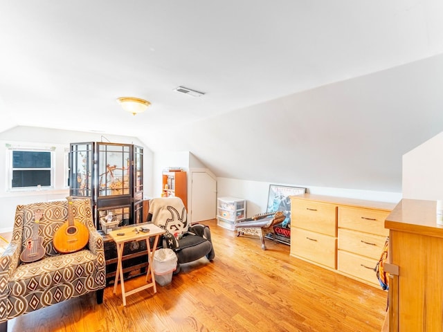 additional living space with light wood-type flooring, visible vents, and vaulted ceiling