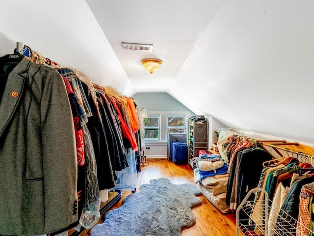 spacious closet with lofted ceiling, visible vents, and wood finished floors