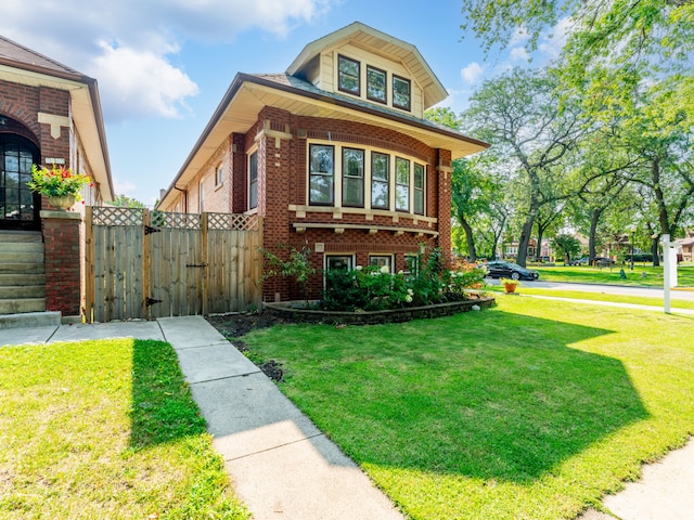 view of front of home with a gate, brick siding, and a front lawn