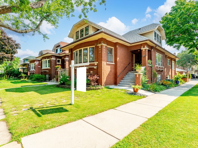 view of front of home featuring roof with shingles, brick siding, and a front lawn