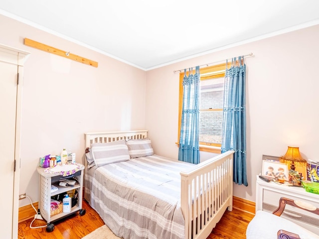 bedroom with ornamental molding and wood finished floors