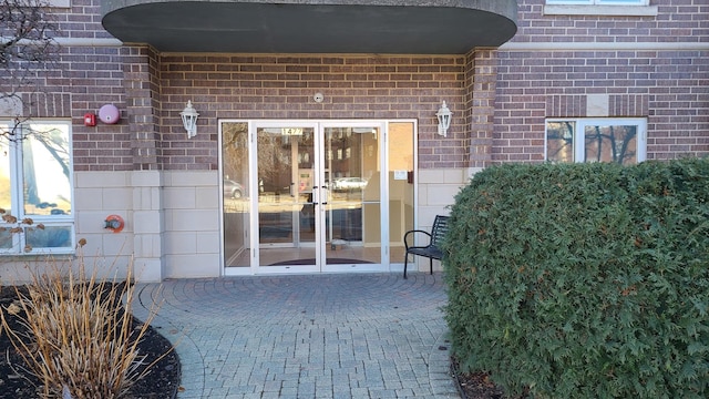 view of exterior entry with french doors, brick siding, and a patio area