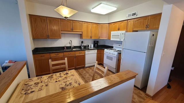 kitchen featuring brown cabinets, visible vents, backsplash, a sink, and white appliances