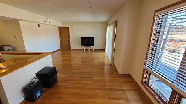 hallway with light wood-type flooring, baseboards, and visible vents