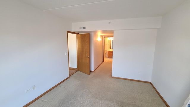 spare room featuring visible vents, light colored carpet, and baseboards