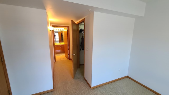 hall featuring light colored carpet and baseboards