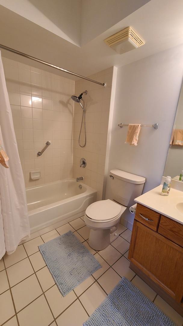 full bathroom with tile patterned flooring, toilet, vanity, visible vents, and shower / bath combo with shower curtain