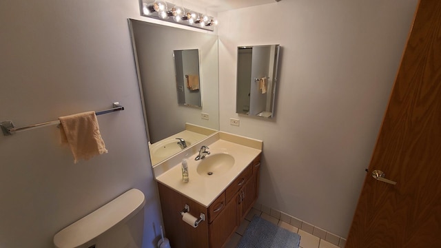 bathroom with tile patterned flooring, baseboards, vanity, and toilet