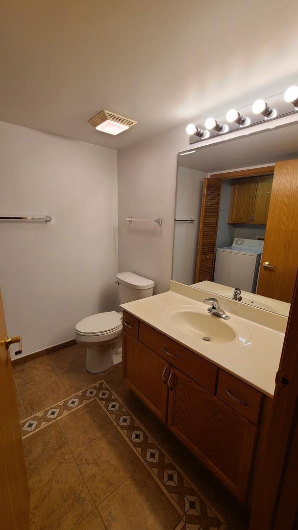 bathroom with baseboards, toilet, washer / clothes dryer, tile patterned floors, and vanity