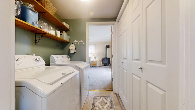 washroom with light carpet, separate washer and dryer, laundry area, light tile patterned floors, and a wood stove