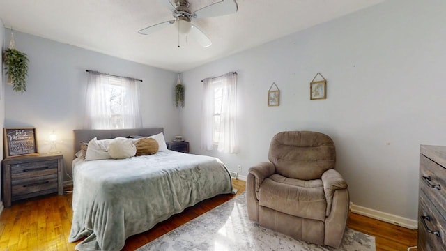 bedroom with a ceiling fan, wood finished floors, and baseboards