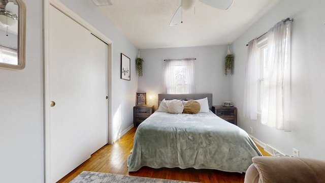 bedroom with baseboards, multiple windows, wood finished floors, and a ceiling fan