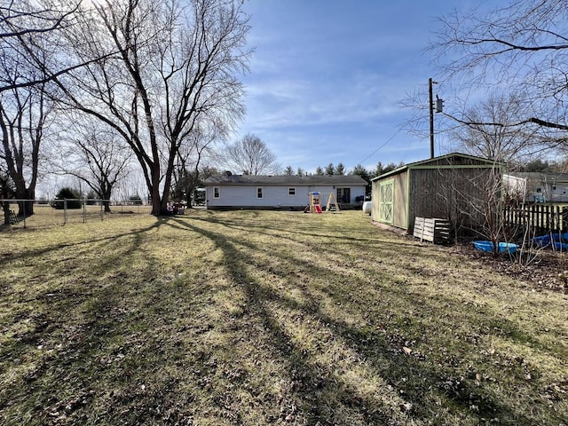 view of yard featuring fence, an outdoor structure, and a playground