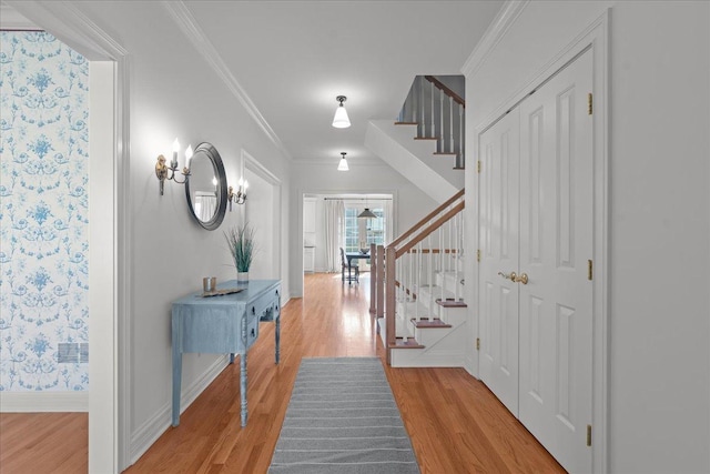 corridor with baseboards, crown molding, stairs, visible vents, and light wood finished floors