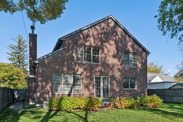 rear view of house featuring a yard, fence, brick siding, and a chimney
