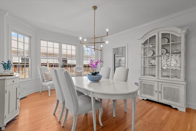dining room with light wood finished floors, crown molding, an inviting chandelier, and a wealth of natural light