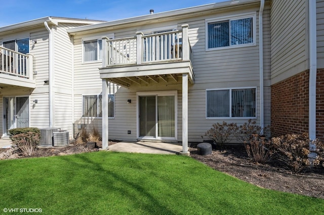 rear view of property featuring brick siding, a yard, a balcony, and a patio