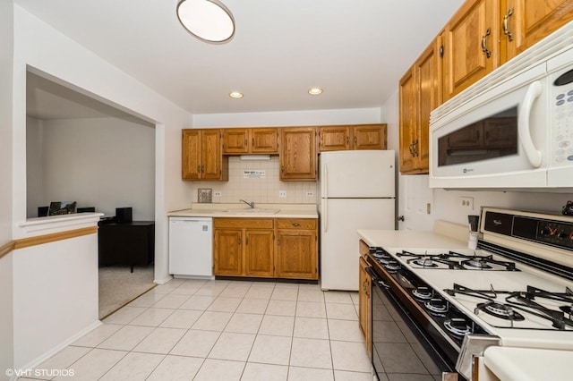 kitchen with brown cabinets, white appliances, light countertops, and a sink