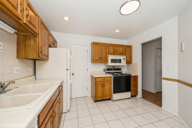 kitchen with white appliances, a sink, light countertops, backsplash, and brown cabinetry