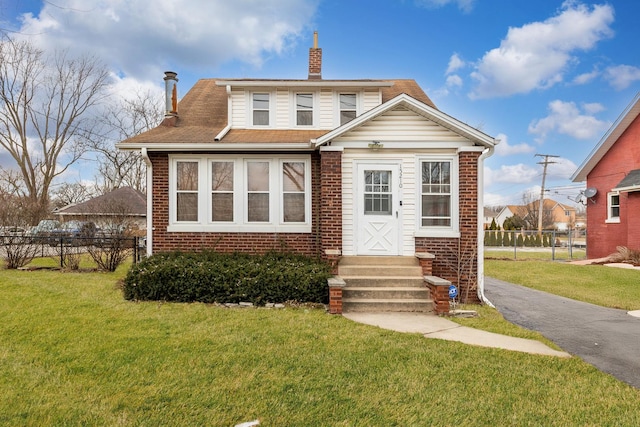 bungalow-style home with entry steps, fence, a front lawn, and brick siding