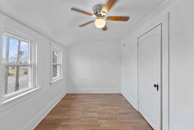 unfurnished room featuring baseboards, a ceiling fan, lofted ceiling, ornamental molding, and light wood-type flooring