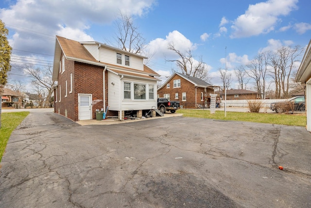 rear view of house with brick siding and a lawn