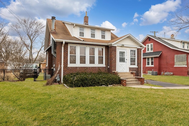 view of front of house with brick siding, a chimney, a front lawn, and fence