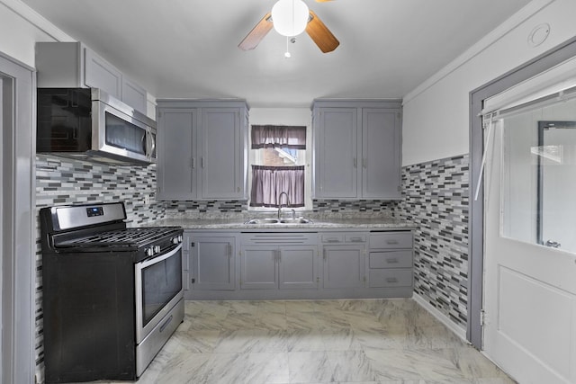 kitchen featuring stainless steel appliances, light countertops, a sink, and gray cabinetry