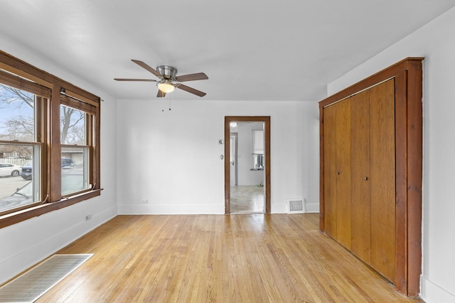 interior space featuring a ceiling fan, baseboards, visible vents, and light wood finished floors