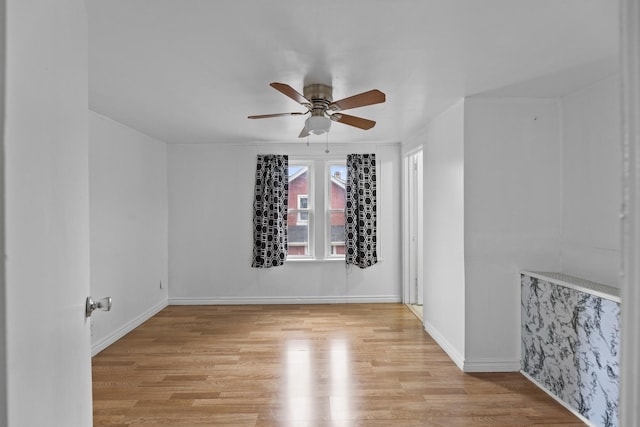 spare room featuring ceiling fan, baseboards, and light wood-style floors