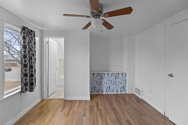 unfurnished room with baseboards, plenty of natural light, visible vents, and wood finished floors