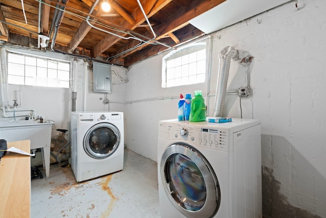 laundry area featuring laundry area, washing machine and dryer, electric panel, and a sink