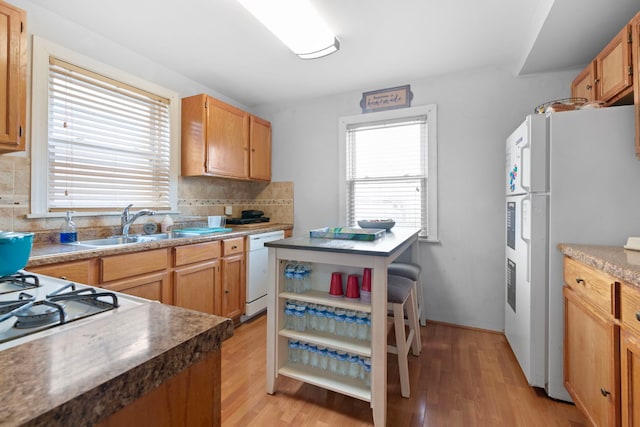 kitchen featuring light wood-style flooring, white appliances, a sink, decorative backsplash, and open shelves