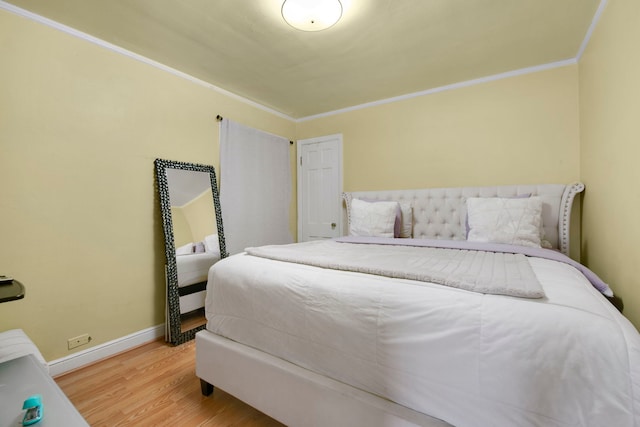 bedroom with ornamental molding, baseboards, and wood finished floors