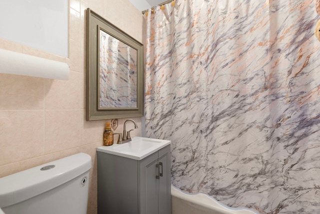 full bath with toilet, shower / tub combo, tile walls, and vanity