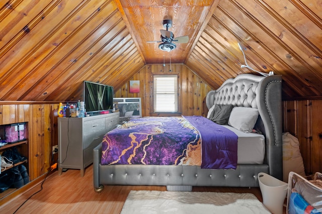 bedroom with lofted ceiling, wood finished floors, and wooden walls