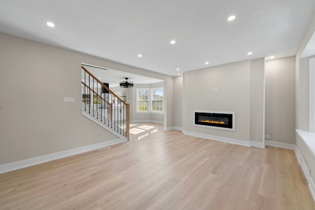 unfurnished living room featuring light wood-style flooring, recessed lighting, visible vents, and stairway