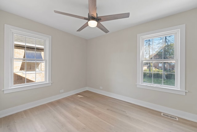 empty room featuring light wood finished floors, baseboards, visible vents, and ceiling fan