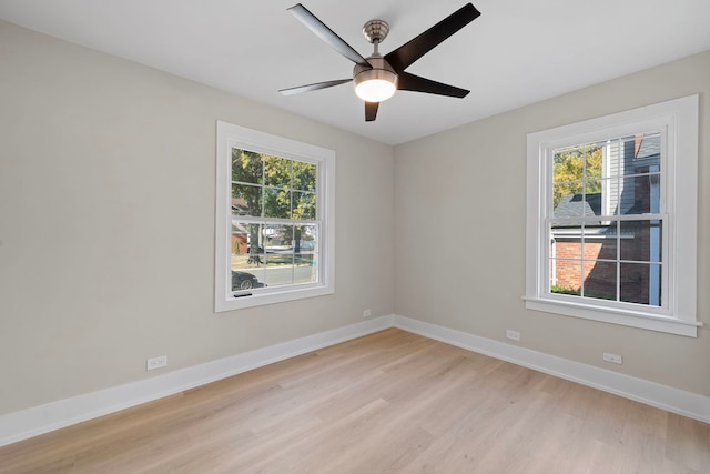 spare room with light wood-style floors, a healthy amount of sunlight, ceiling fan, and baseboards